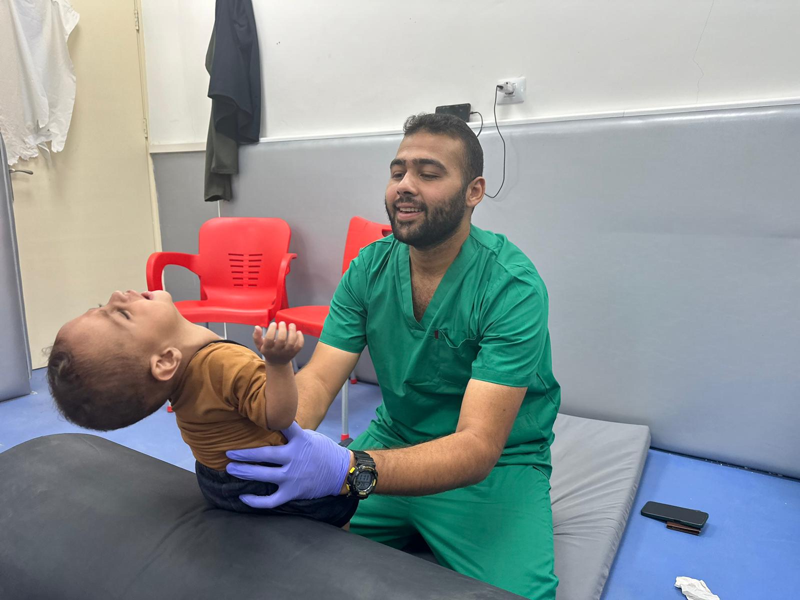 A staff member at Al Ahli Hospital checks a little boy who has been brought in by his father. © Al Ahli Hospital. Used with permission.