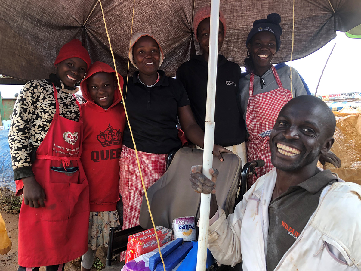 Collins has the support of his friends at the market. © Julianne Stewart/AID.