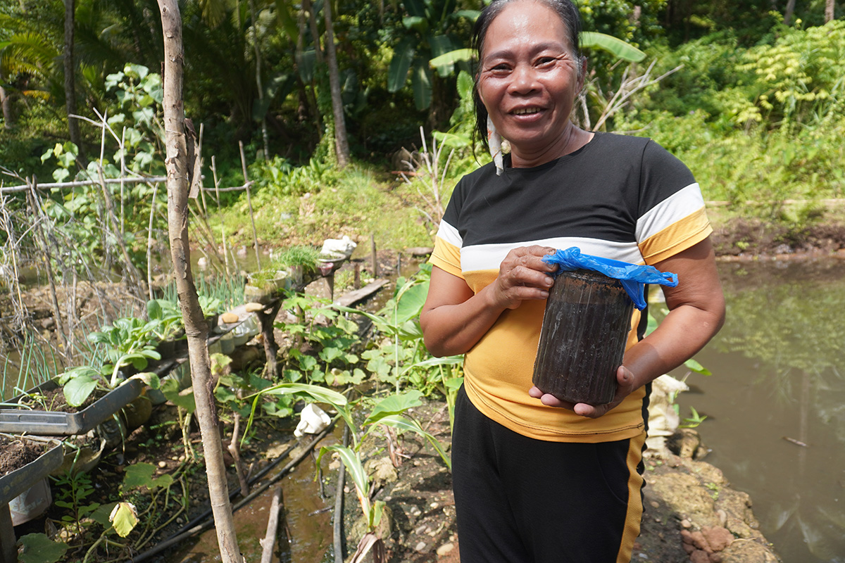 Marietta shows a container of fish amino acid she uses as crop fertilizer and pesticide. © IFI-VIMROD. Used with permission.