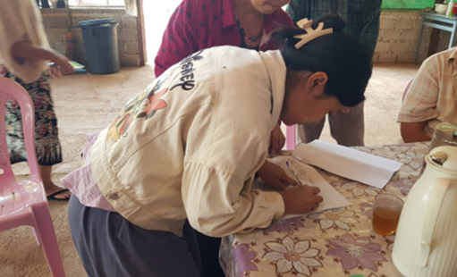 Woman signs for cash relief from the Church of the Province of Myanmar. © CPM. Used with permission.