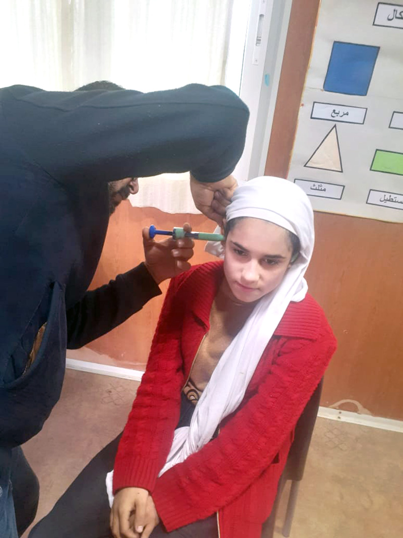 A hearing technician takes the measurement of another child at the refugee camp. © Holy Land Institute for the Deaf. Used with permission.