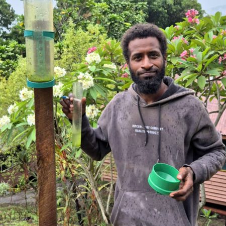 Brother Richard SSF at La Verna Anglican Franciscan Friary near Honiara checks the Friary’s rain gauge to provide data to ACOM as part of their climate change data collection work. © Brother Christopher John SSF. Used with permission.