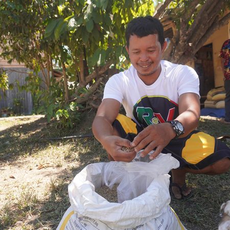 Edgar opens a bag of traditional, drought-resistant black rice that his community group grew in Bohol, the Philippines. © IFI-VIMROD. Used with permission.